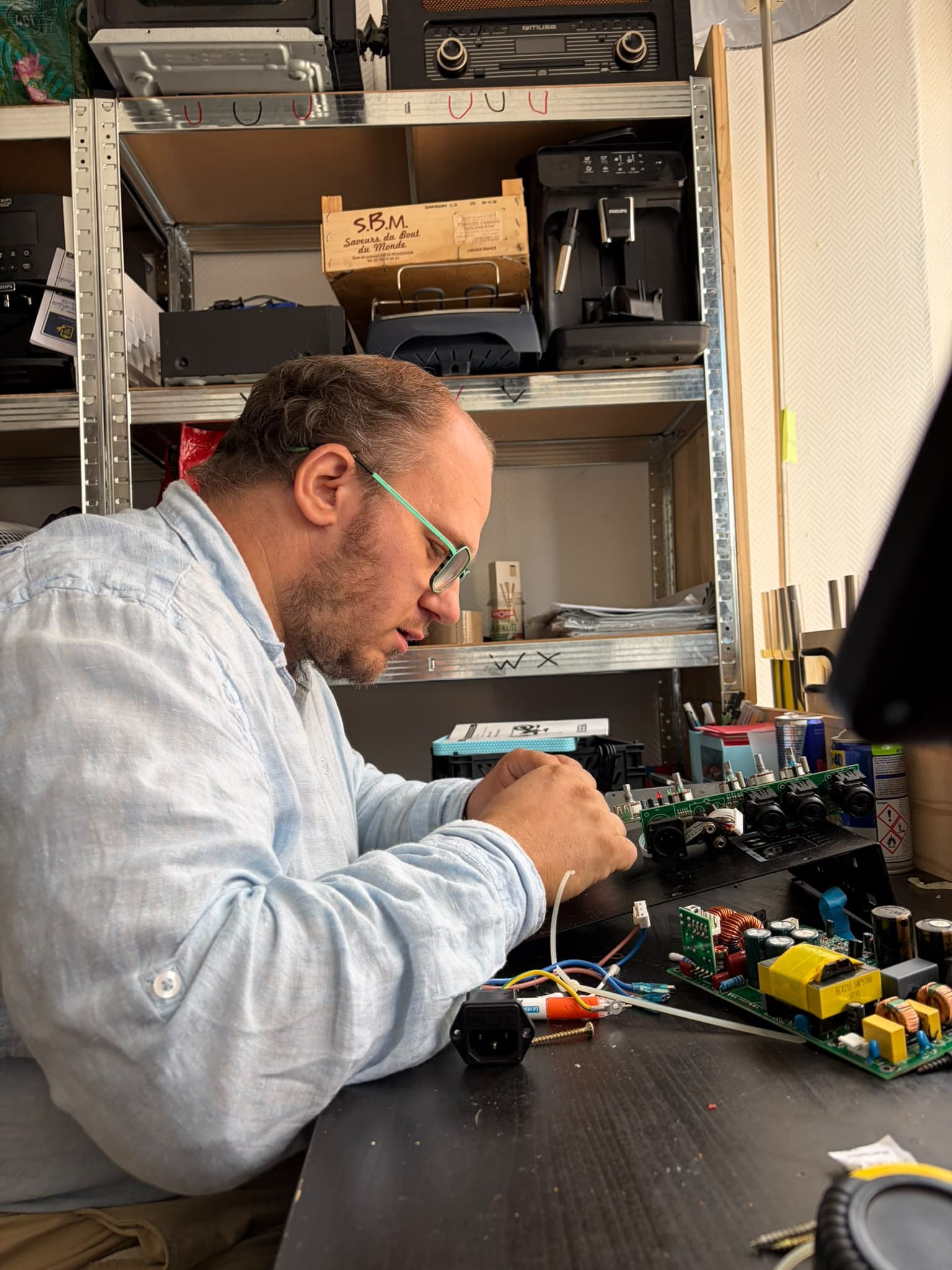 Philippe répare un appareil électronique sur son établi, à Saint-Amand-les-Eaux.